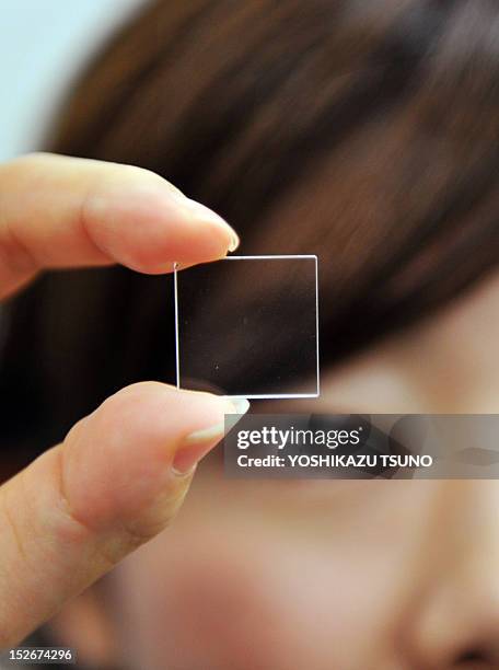 Woman holds up Japan's electronics giant Hitachi's newly unveiled quartz glass plate technology, which can be used for the indefinite storage of...
