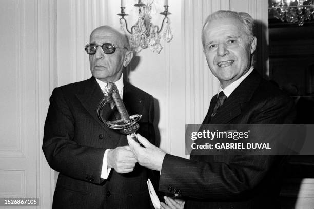 French Man of letters Robert Aron receives the Academie Française sword from Jean Mistler, perpetual secretary of the Academie, on March 7, 1974 in...