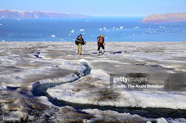 Researchers walk towards a glacier while a stream made by the melting glacier on July 19, 2012 near Qaanaaq, Greenland. In Greenland there is said to...