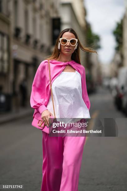 Maria Rosaria Rizzo wears beige sunglasses, a white squared neck tank-top, a neon pink silk puffy sleeves / cropped blouse, matching neon pink silk...