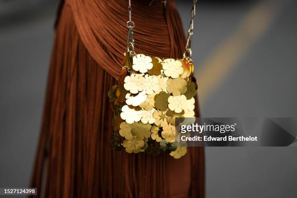 Katya Tolstova wears a brown camel fringed wrap / heart neck / long dress, a gold embroidered large sequined shoulder bag from Paco Rabanne, outside...