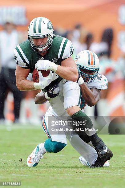 Tight end Konrad Reuland of the New York Jets carries the ball after catching a pass and is tackled by cornerback Sean Smith of the Miami Dolphins...