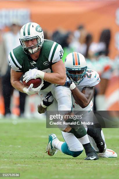 Tight end Konrad Reuland of the New York Jets carries the ball after catching a pass and is tackled by cornerback Sean Smith of the Miami Dolphins...