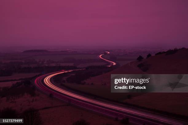 view of moving traffic light trails on m40 at dusk, from chiltern hills. oxford, oxfordshire, england, uk - mr purple stock pictures, royalty-free photos & images