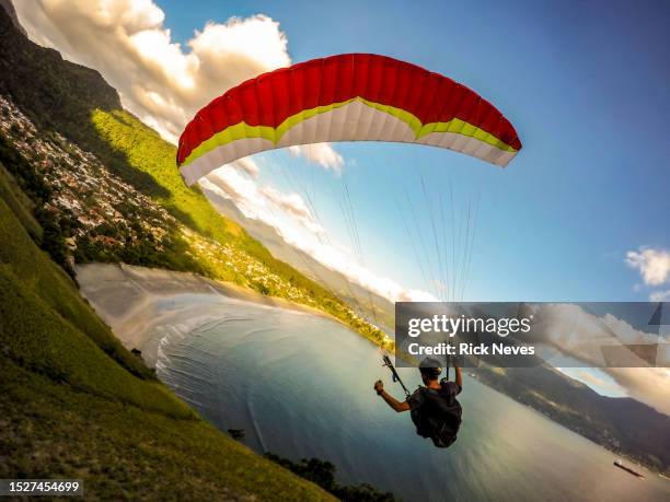 extreme paraglider pilot flying over the beach. - glider stock pictures, royalty-free photos & images