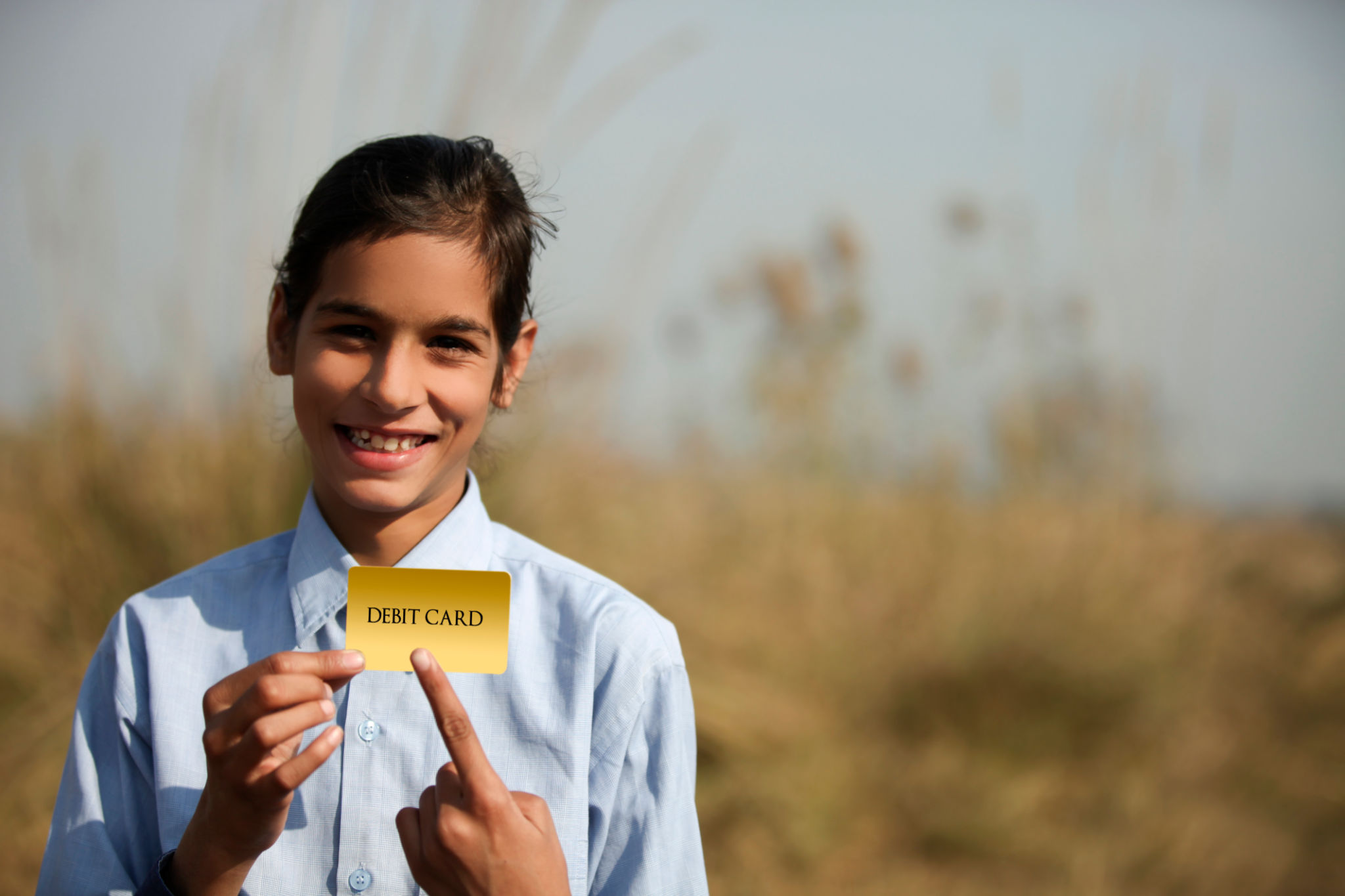 Elementary age cheerful child holding debit card in hands Elementary age cheerful child holding debit card in hands