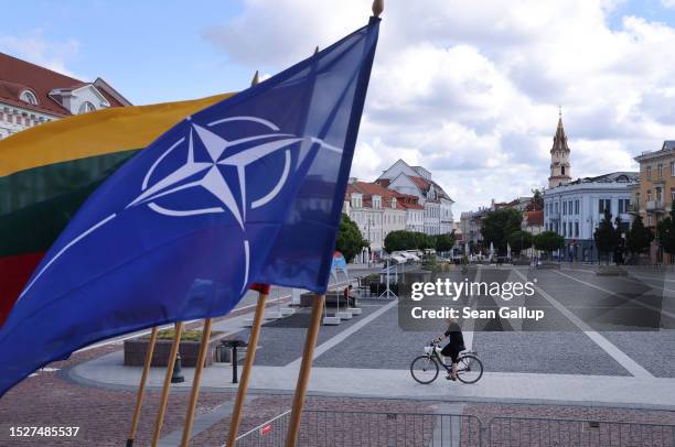 Woman rides a bicycle past the NATO and Lithuanian flags on July 09, 2023 in Vilnius, Lithuania. Vilnius is scheduled to host the July NATO Summit.