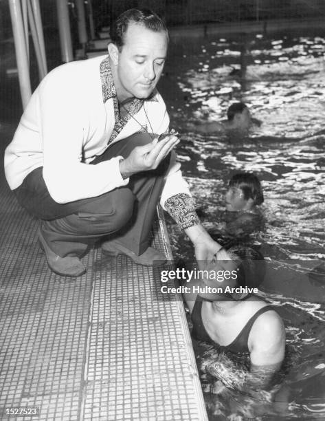 Commonwealth and Empire Games, Cardiff. Australian Swimming coach Harry Gallagher checks the pulse of swimmer Dawn Fraser after a training session....