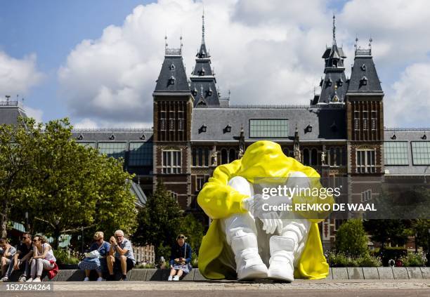 Pedestrians sit next to an artwork named "The Silent Struggle" by Power of Art House on the Museumplein, which symbolizes the inner struggle that...