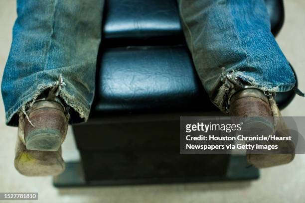 Bull riding athlete Beau Schroeder's boots and spurs dangle off the chiropractic table while he gets treatment at the Rodeo Houston sports medicine...