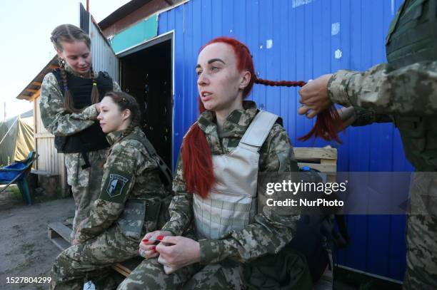 Ukrainian female cadets wearing new military uniforms that was designed for women have their hair braided before a training session at a shooting...