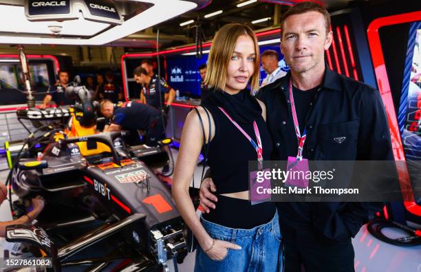 Sam Worthington and Lara Worthington pose for a photo in the Red Bull Racing garage prior to the F1 Grand Prix of Great Britain at Silverstone...