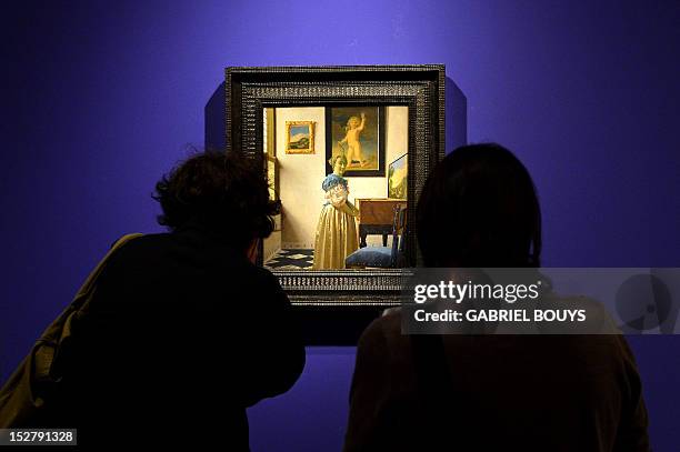 Visitors look at "A Young Woman Standing at a Virginal" by Dutch artist Johannes Vermeer during the media preview of the exhibition of "Vermeer. Il...