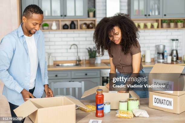 couple placing groceries into charity donation boxes - de clutter stock pictures, royalty-free photos & images