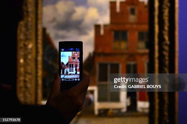 Visitor takes a picture of "The Little Street" by Dutch artist Johannes Vermeer on September 26, 2012 during the media preview of the exhibition of...