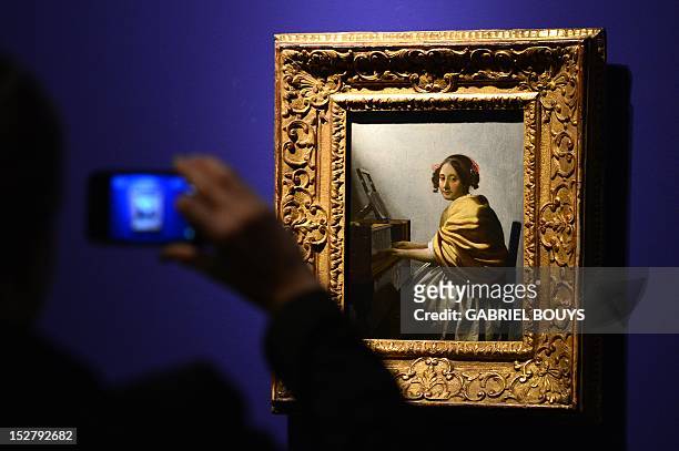 Visitor takes a picture of "Young Woman Seated at the Virgina" by Dutch artist Johannes Vermeer on September 26, 2012 during the media preview of the...