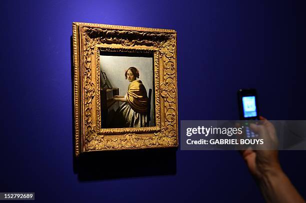 Visitor takes a picture of "Young Woman Seated at the Virginals" by Dutch artist Johannes Vermeer on September 26, 2012 during the media preview of...