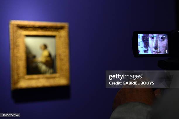 Visitor takes a picture of "Young Woman Seated at the Virgina" by Dutch artist Johannes Vermeer on September 26, 2012 during the media preview of the...