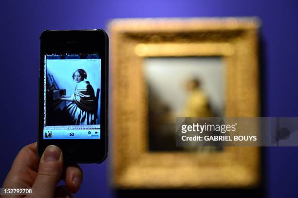 Visitor takes a picture of "Young Woman Seated at the Virginals" by Dutch artist Johannes Vermeer on September 26, 2012 during the media preview of...