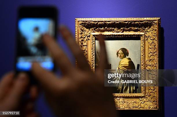 Visitor takes a picture of "Young Woman Seated at the Virginals" by Dutch artist Johannes Vermeer on September 26, 2012 during the media preview of...