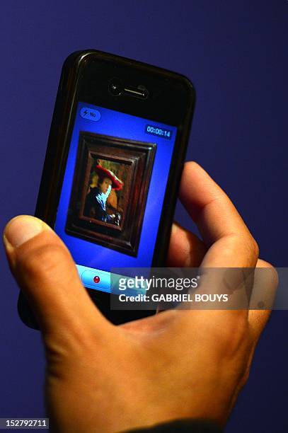 Visitor takes a picture of "Girl with the Red Hat" by Dutch artist Johannes Vermeer on September 26, 2012 during the media preview of the exhibition...