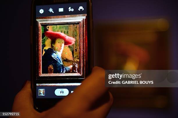 Visitor takes a picture of "Girl with the Red Hat" by Dutch artist Johannes Vermeer on September 26, 2012 during the media preview of the exhibition...