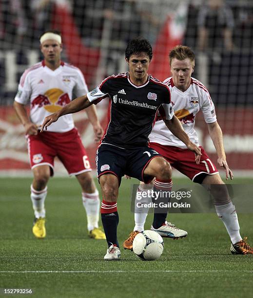 Ryan Guy of the New England Revolution keeps the ball away from Teemu Tainio and Dax McCarty of the New York Red Bulls at Gillette Stadium September...