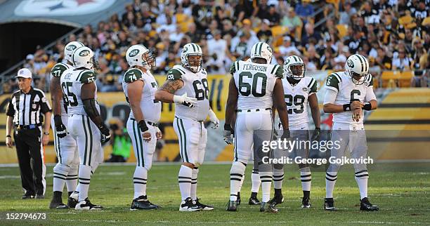 Quarterback Mark Sanchez of the New York Jets looks at a play list attached to his wrist as members of the offense, including offensive linemen...