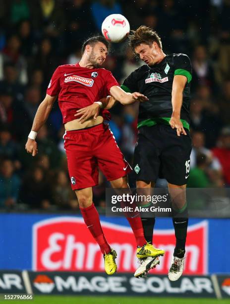 Daniel Caligiuri of Freiburg jumps for a header with Sebastian Proedl of Bremen during the Bundesliga match between SC Freiburg and SV Werder Bremen...