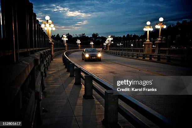 lone car on night drive on curved bridge - pasadena los angeles stockfoto's en -beelden