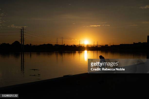 Woman watches a large bird fly over Tempe Town Lake during a recording-breaking heat wave on July 12, 2023 in Tempe, Arizona. Tuesday marked the...