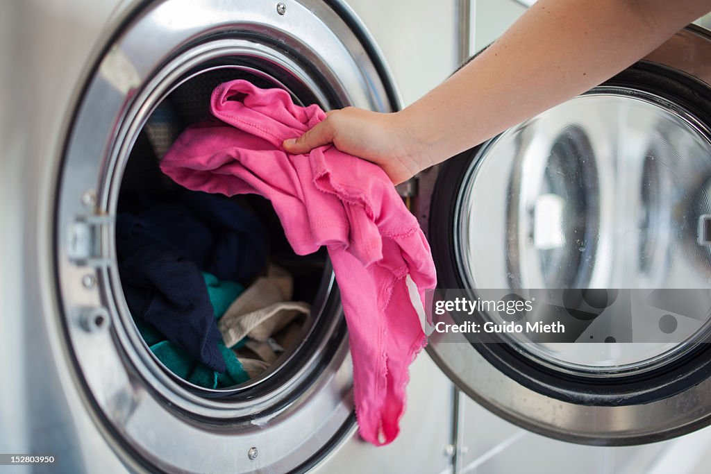 Woman putting shirt into washing machine