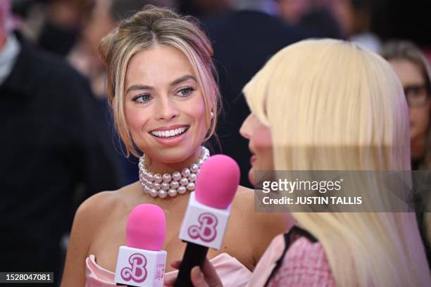 Australian actress Margot Robbie speaks to a TV presenter on the pink carpet upon arrival for the European premiere of "Barbie" in central London on...