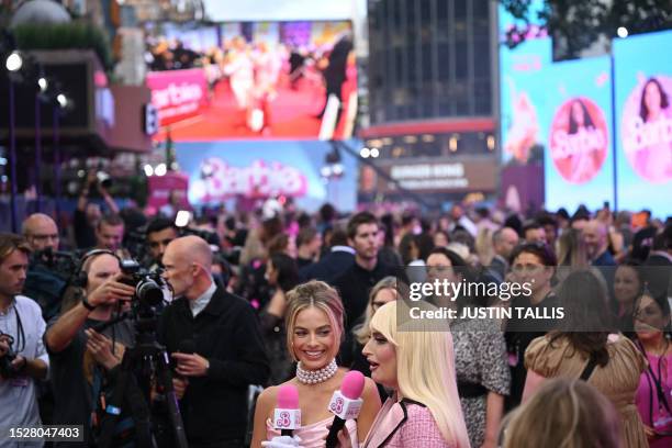 Australian actress Margot Robbie speaks to a TV presenter on the pink carpet upon arrival for the European premiere of "Barbie" in central London on...