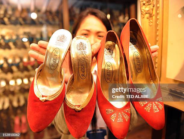 Museum employee displays some of the shoes of former Philippine first lady Imelda Marcos, next to her portrait at the shoe museum in Manila on...