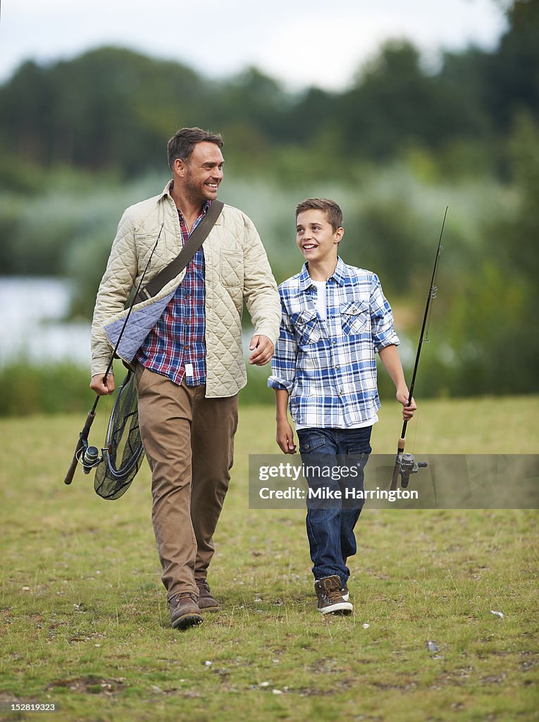 Father and son walking with fishing rods.