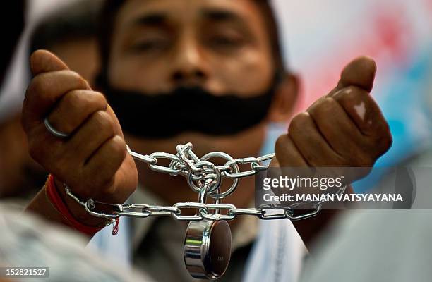 Indian traders cover their mouths with black cloth and handcuff themselves protesting against the Indian Government's decision to allow Foreign...