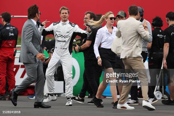 Brad Pitt, star of the upcoming Formula One based movie, Apex, and Javier Bardem talk on the grid during the F1 Grand Prix of Great Britain at...