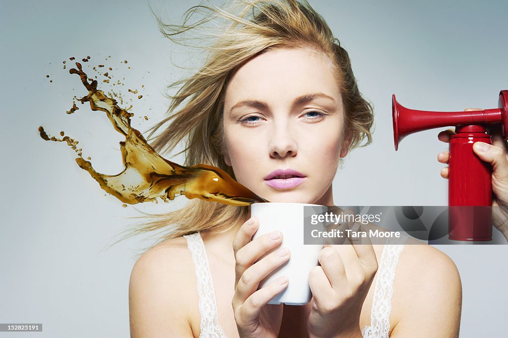 Tired woman staying awake with coffee and air horn