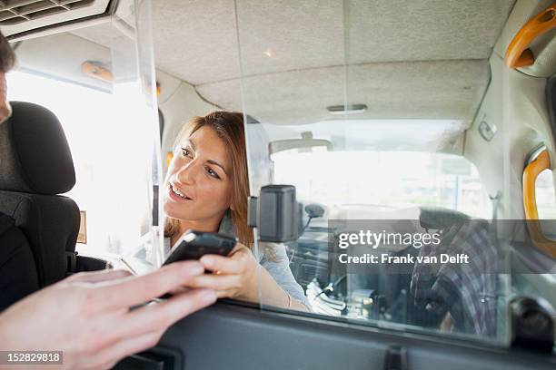 woman handing cell phone to taxi driver - london taxi stock pictures, royalty-free photos & images