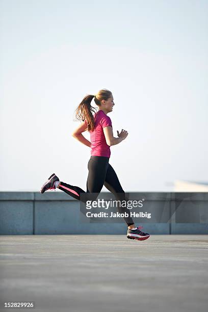 woman running on rooftop - running side view stock pictures, royalty-free photos & images