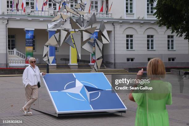 People snap photos of each other at a sculpture dedicated to the NATO military alliance in front of the Presidential Palace on July 09, 2023 in...