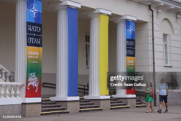 People walk past columns of the Presidential Palace showing the blue and yellow of the Ukrainian flag as well as banners for the upcoming NATO summit...