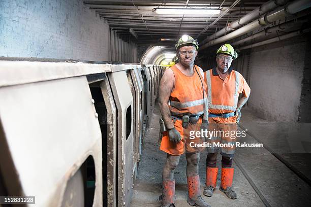 portrait of coalminers working next to train in deep mine - coal miner stock pictures, royalty-free photos & images