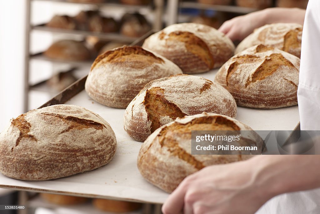 Chef carrying tray of bread in kitchen