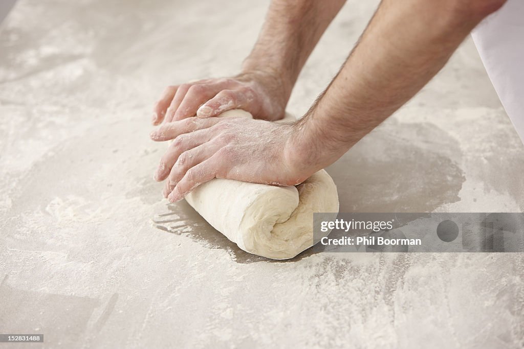 Chef kneading dough in kitchen