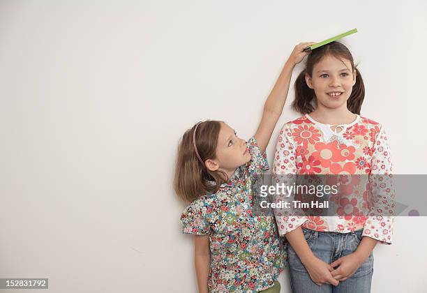 girl measuring taller sister - due sorelle foto e immagini stock