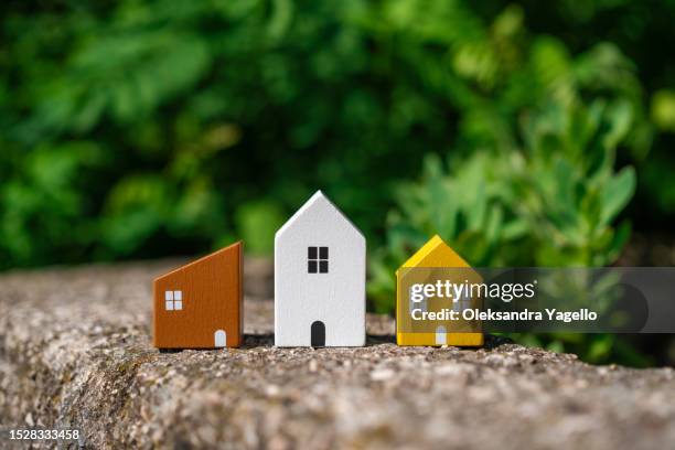 tiny three house models on background of green grass. real estate business. options for houses to buy - business model strategy stockfoto's en -beelden