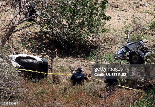 Forensic employees work at the site of an explosive attack against a police patrol in Tlajomulco de Zuñiga, a suburb at the city of Guadalajara,...