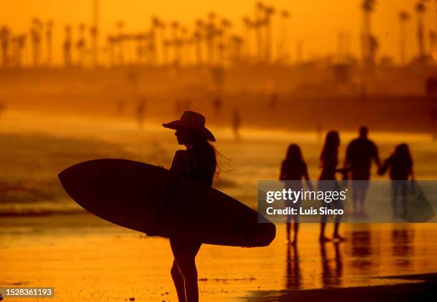 Beachgoers take in the cooling mist of the ocean as the sun sets on Huntington Beach. Southern California weather is expected to get hotter in coming...